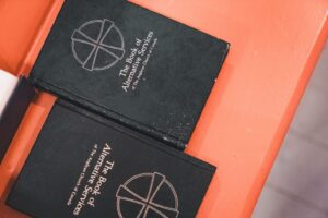 Two religious books from the Anglican Church on a vibrant surface.